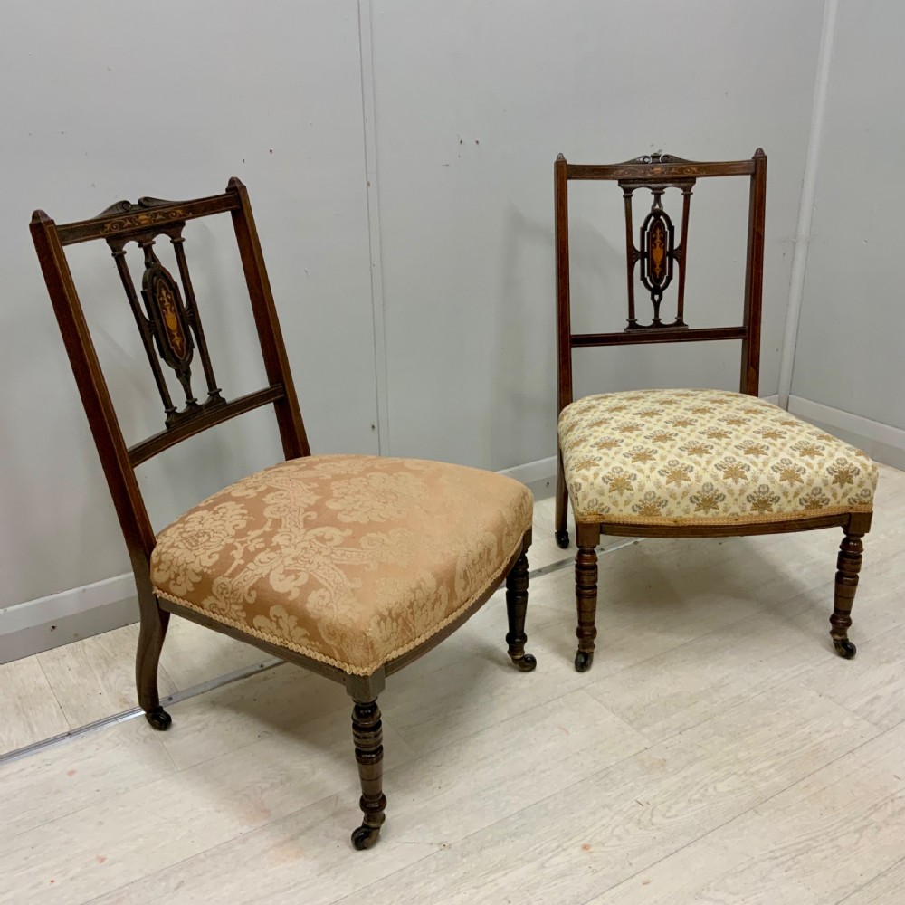 A pair of Edwardian inlaid mahogany nursing chairs featuring splats decorated with marquetry, padded upholstered seats, and turned front legs on castors. View III