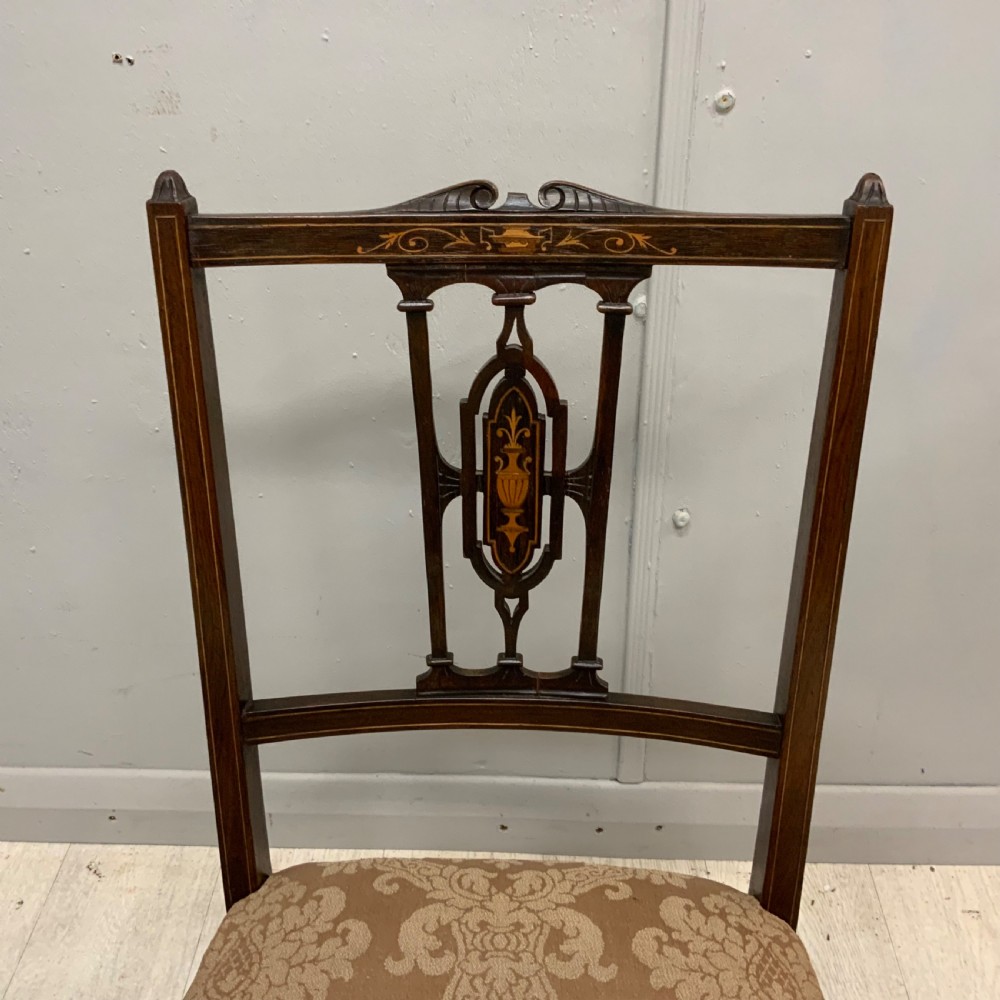 A pair of Edwardian inlaid mahogany nursing chairs featuring splats decorated with marquetry, padded upholstered seats, and turned front legs on castors. View IV