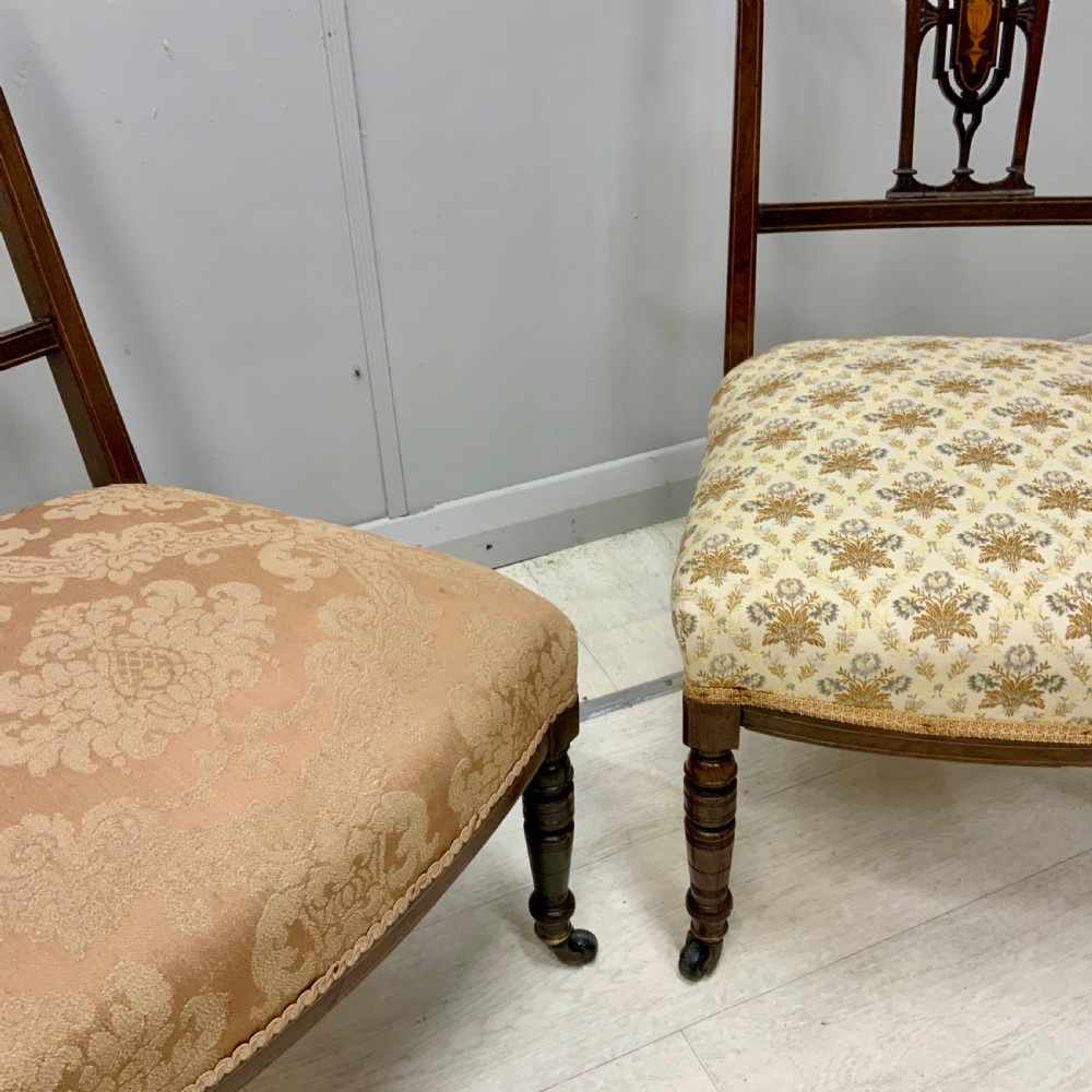 A pair of Edwardian inlaid mahogany nursing chairs featuring splats decorated with marquetry, padded upholstered seats, and turned front legs on castors. View V