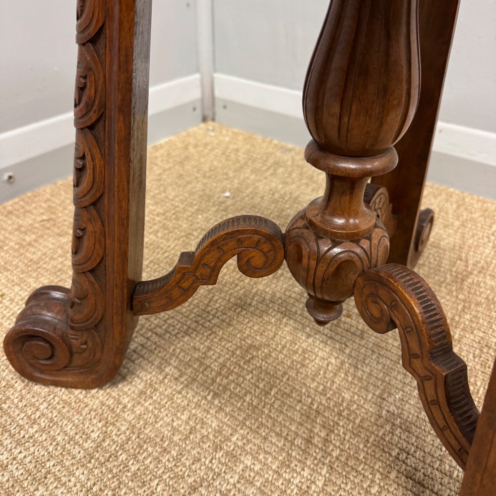 A carved dark hardwood revolving piano stool featuring a circular medallion seat, supported by three carved scroll legs and a central turned column. View VI