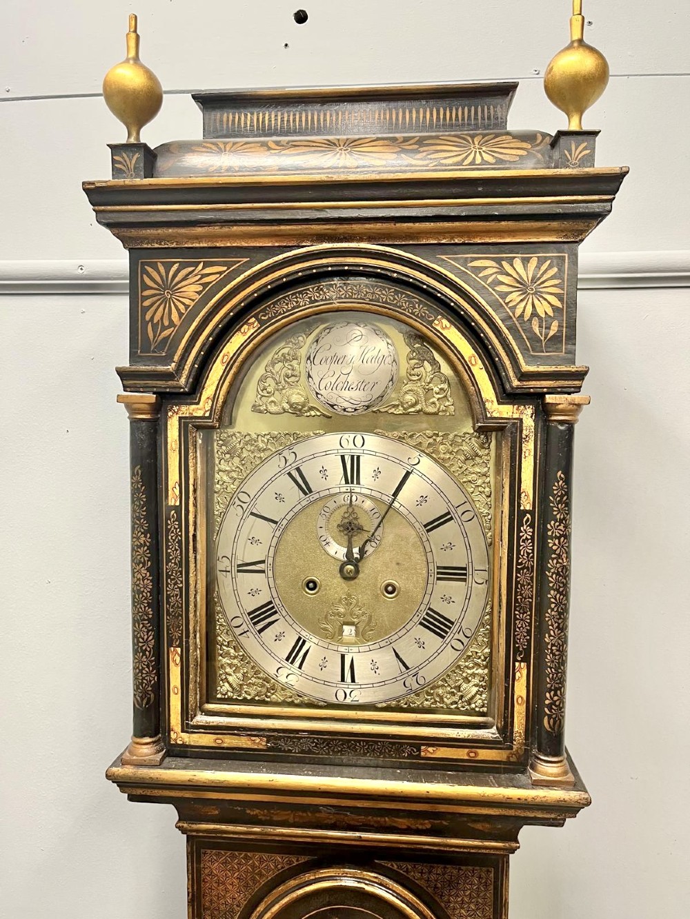 An 18th-century black lacquered longcase clock featuring gilt chinoiserie artwork, brass finials, and an arched brass dial. View III