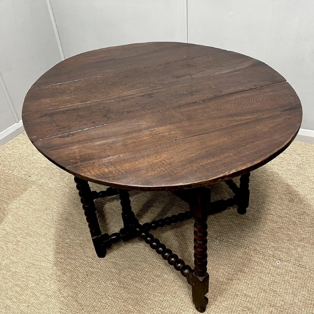A dark oak gateleg table featuring an oval drop-leaf top, bobbin-turned legs, and matching turned stretchers. View II
