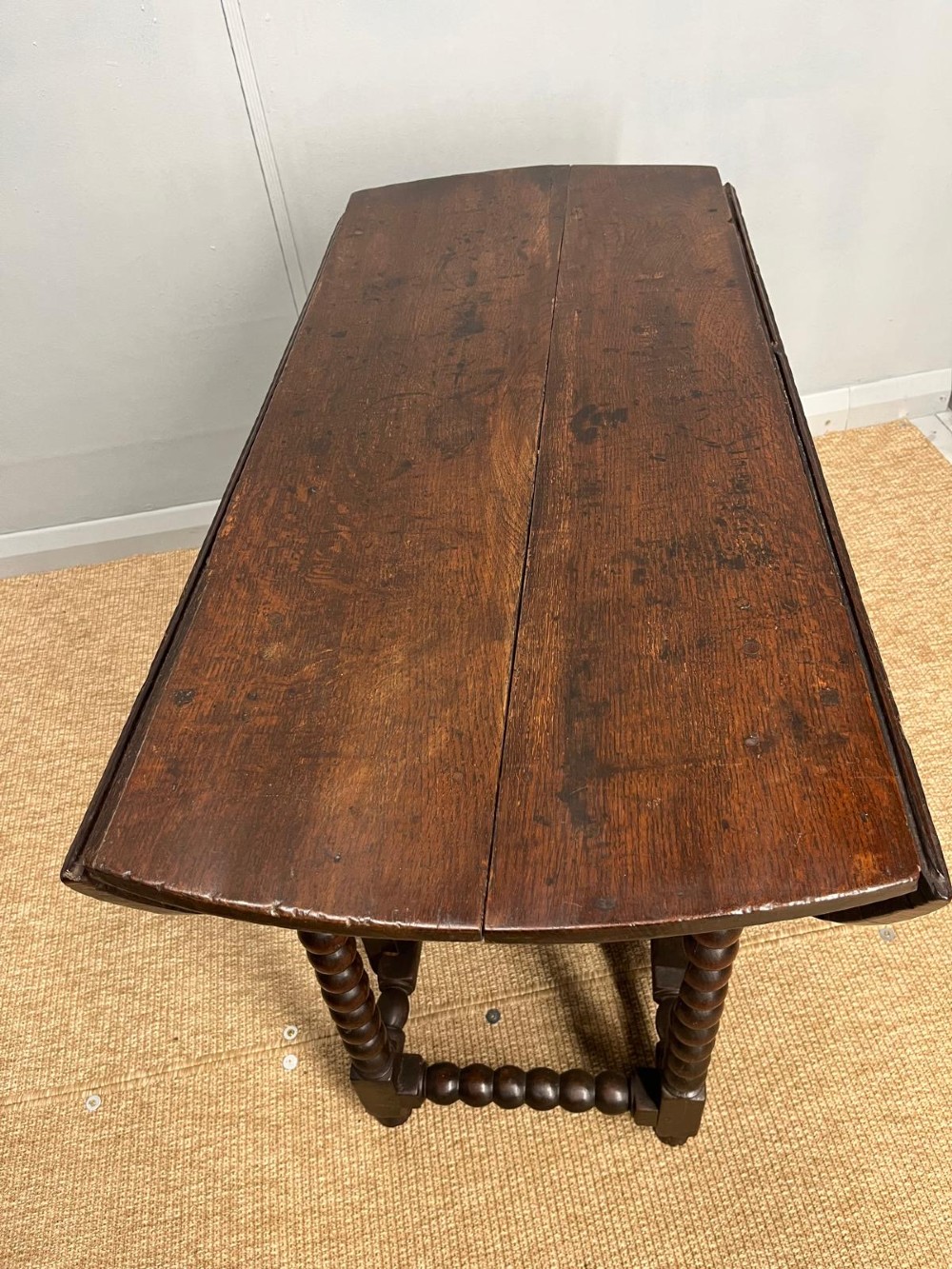 A dark oak gateleg table featuring an oval drop-leaf top, bobbin-turned legs, and matching turned stretchers. View III