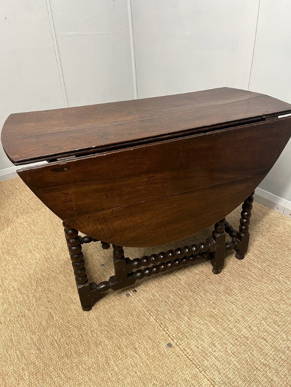 A dark oak gateleg table featuring an oval drop-leaf top, bobbin-turned legs, and matching turned stretchers. View IV