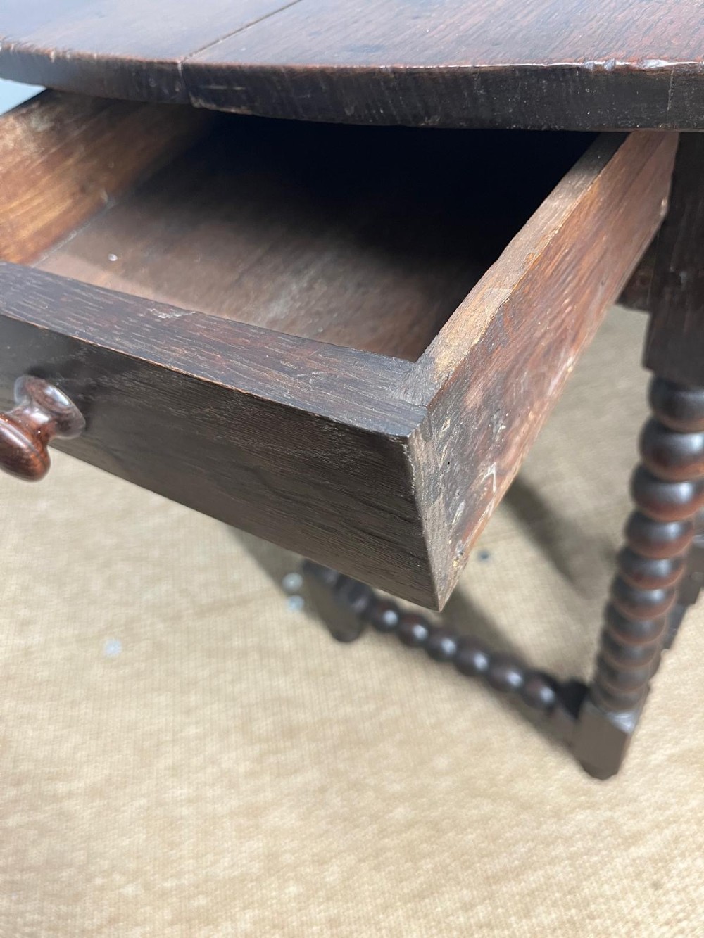 A dark oak gateleg table featuring an oval drop-leaf top, bobbin-turned legs, and matching turned stretchers. View VII