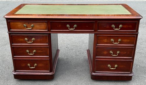 fig 1. A Victorian mahogany pedestal writing desk featuring nine drawers with brass swan-neck handles and a green gold-tooled leather writing surface.
