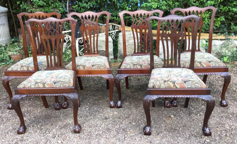 A set of six mahogany Chippendale style dining chairs featuring carved pierced splats and patterned tapestry seats.
