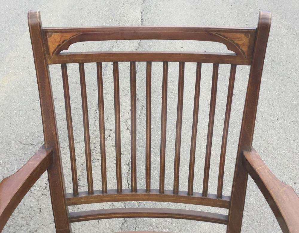 A pair of Edwardian mahogany salon armchairs featuring vertical slatted backs with marquetry inlay details on the top rail and upholstered patterned seats. View V