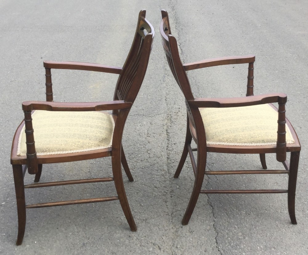 A pair of Edwardian mahogany salon armchairs featuring vertical slatted backs with marquetry inlay details on the top rail and upholstered patterned seats. View X