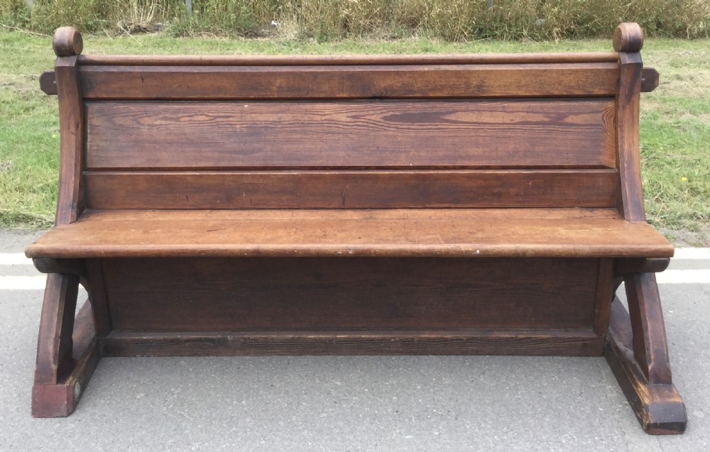 A Victorian pitch pine church bench featuring a solid plank seat, panelled backrest, and shaped side end frames. View III