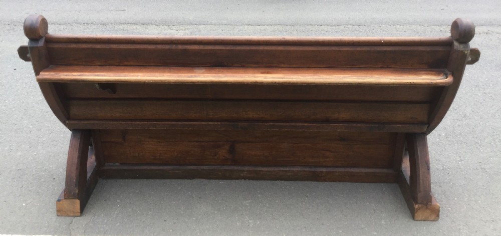 A Victorian pitch pine church bench featuring a solid plank seat, panelled backrest, and shaped side end frames. View VIII