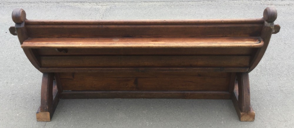 A Victorian pitch pine church bench featuring a solid plank seat, panelled backrest, and shaped side end frames. View IX