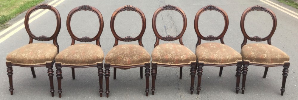 A set of six Victorian balloon-back dining chairs crafted from carved dark walnut wood with upholstered patterned seats and turned front legs. View IV