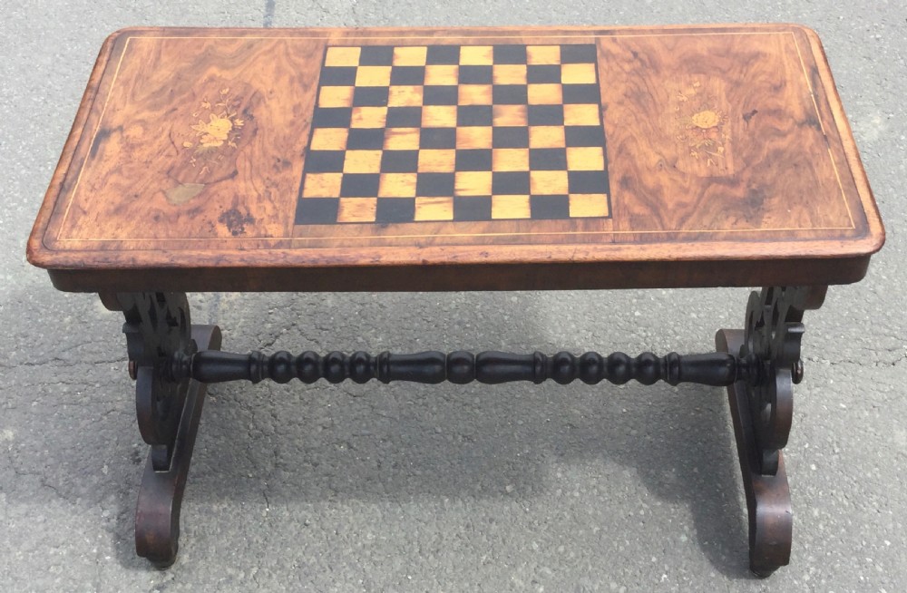 A rectangular Victorian walnut games table featuring a central inlaid chessboard, marquetry side panels, carved trestle ends, and a turned stretcher. View III