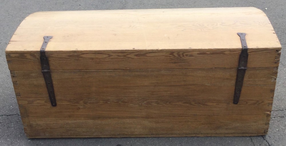 A large rectangular natural pine blanket chest with a rounded domed lid, corner dovetail joints, a central wooden knob, and an iron escutcheon. View IV