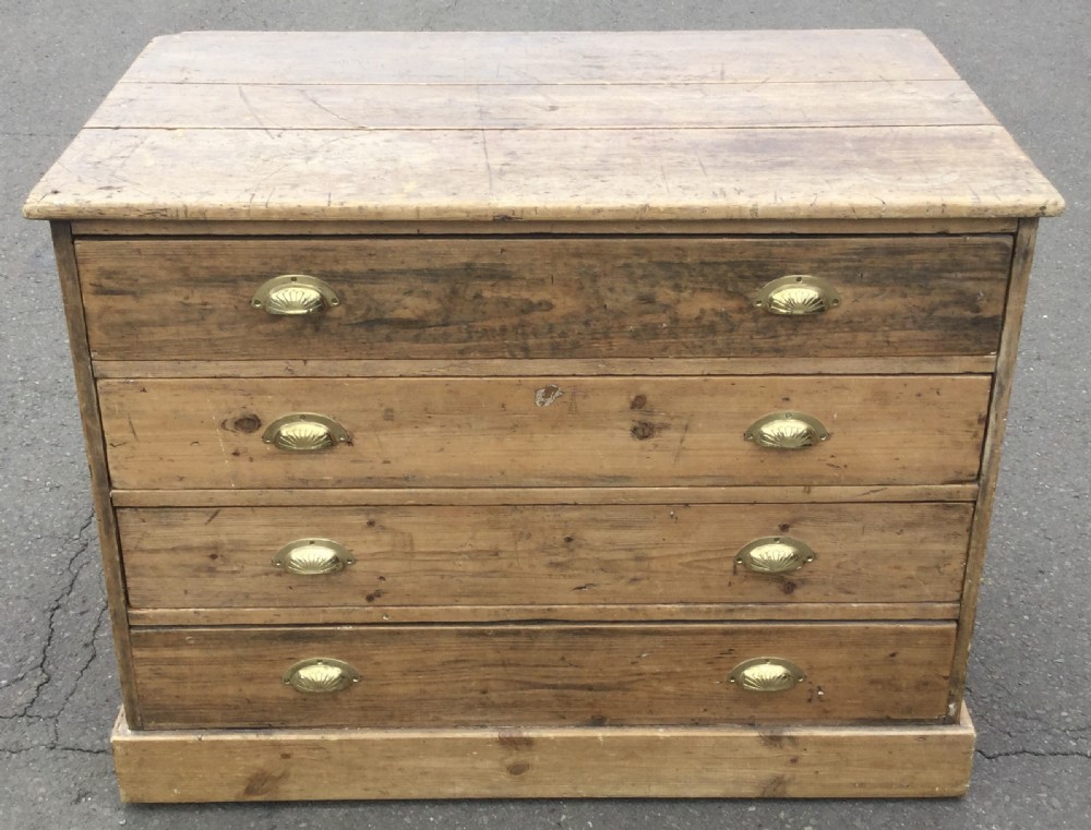 An Edwardian pitch pine plan chest featuring four wide drawers fitted with polished brass shell cup handles.