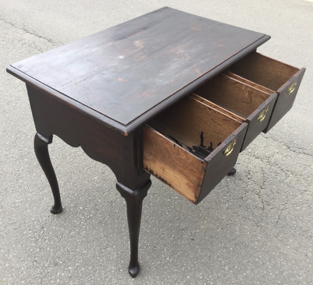 A Georgian dark oak side table featuring three front drawers with brass escutcheon plates, a shaped apron, and cabriole legs ending in pad feet. View X