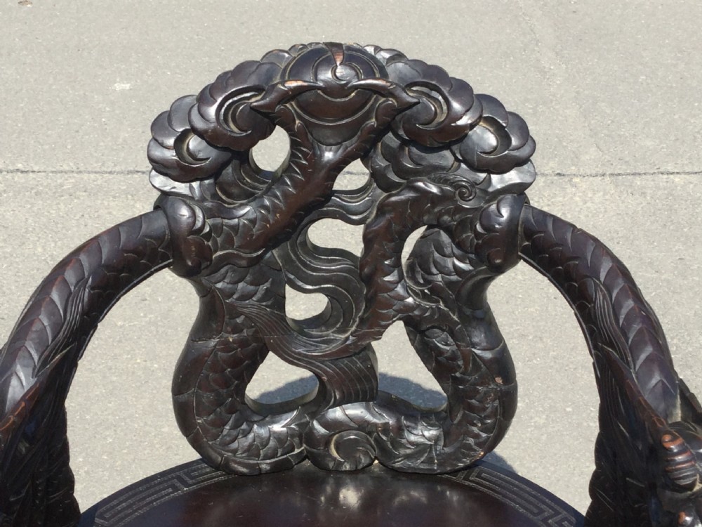 A dark hardwood oriental armchair featuring intricate hand-carved dragon motifs forming the backrest and arms. View X