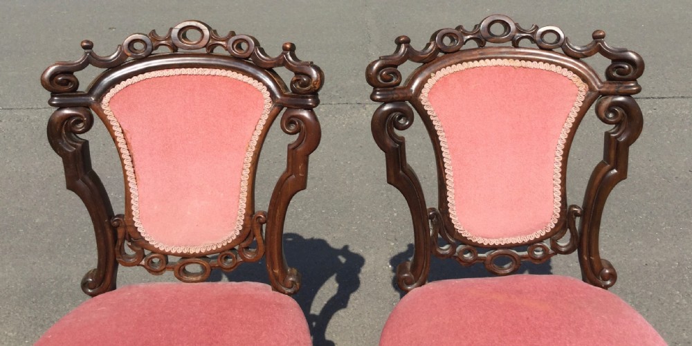 A pair of carved Victorian rosewood side chairs featuring pierced scrollwork backrests, turned legs, and dusty pink velvet upholstery. View IV