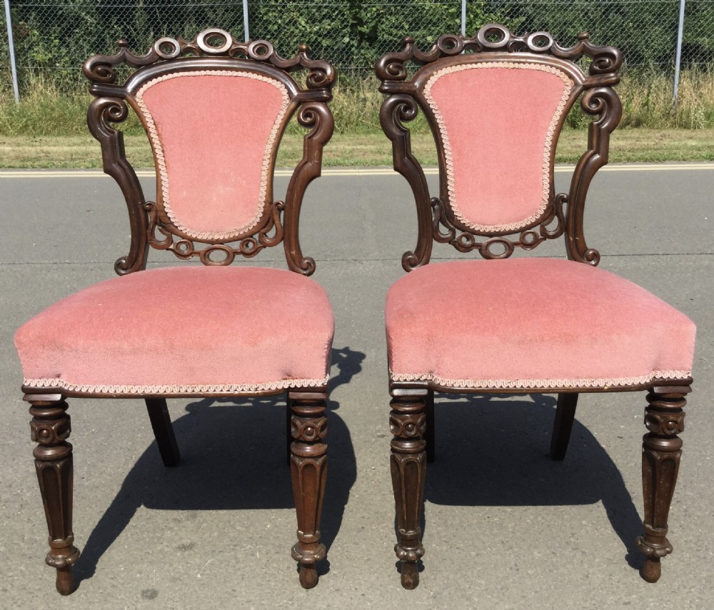 A pair of carved Victorian rosewood side chairs featuring pierced scrollwork backrests, turned legs, and dusty pink velvet upholstery. View V