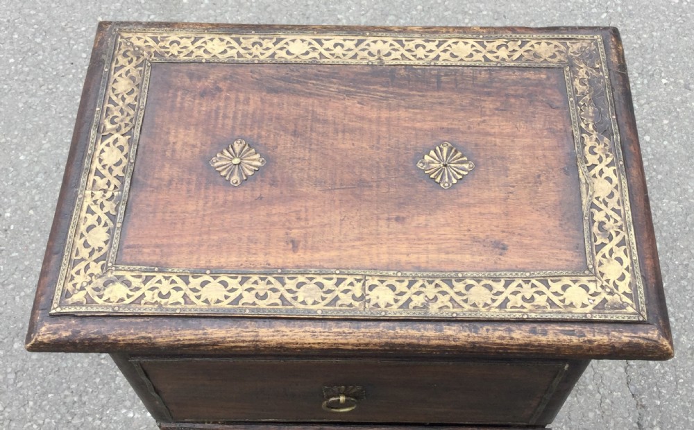 A tall, narrow dark hardwood chest of drawers featuring five stacked drawers with brass ring pulls and shaped bracket feet. View VIII
