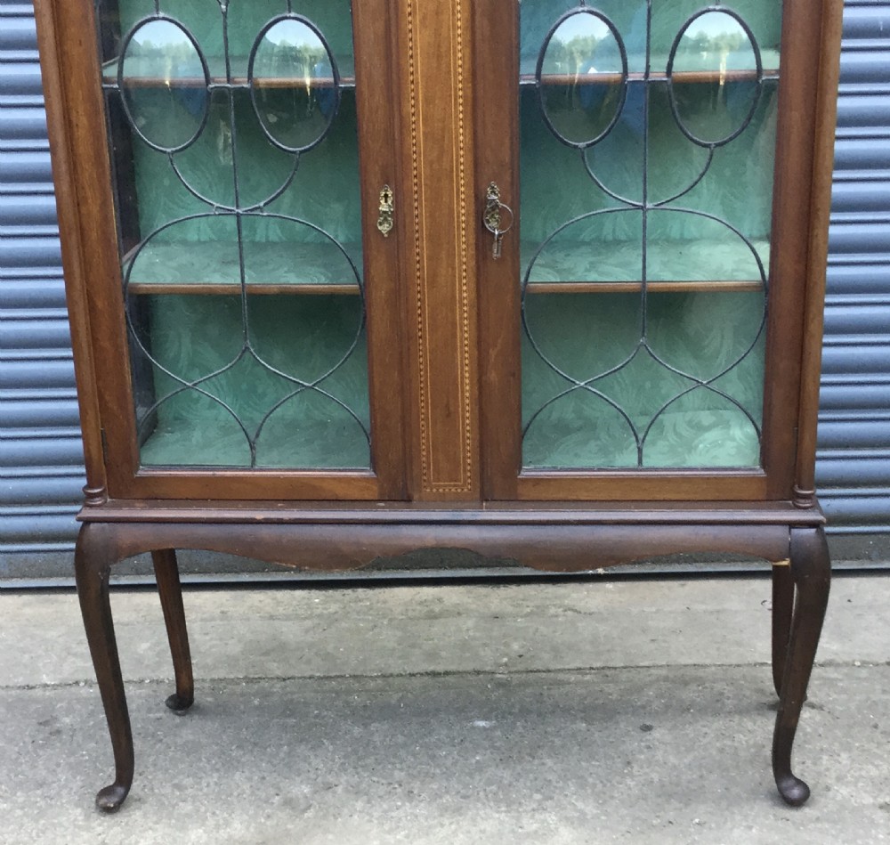An antique mahogany display cabinet with leaded glass doors, delicate marquetry inlay on the pediment, and slender cabriole legs. View IV