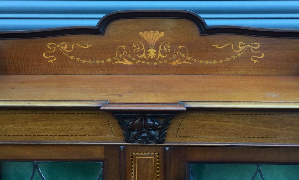An antique mahogany display cabinet with leaded glass doors, delicate marquetry inlay on the pediment, and slender cabriole legs. View VI