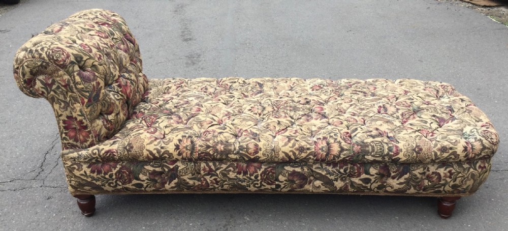 A Victorian upholstered daybed featuring deep-buttoned floral tapestry fabric with a scrolled end rest and turned wooden legs. View V