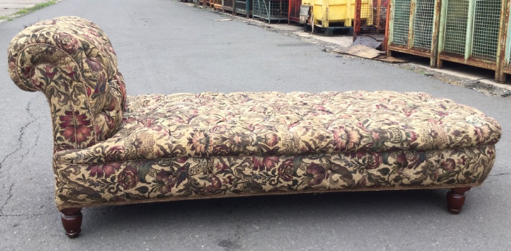 A Victorian upholstered daybed featuring deep-buttoned floral tapestry fabric with a scrolled end rest and turned wooden legs. View VI