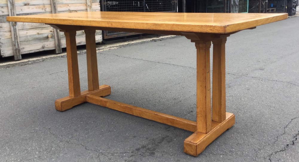 A rectangular golden oak refectory dining table featuring a framed top surface, twin vertical trestle leg supports, and a low central connecting stretcher. View II