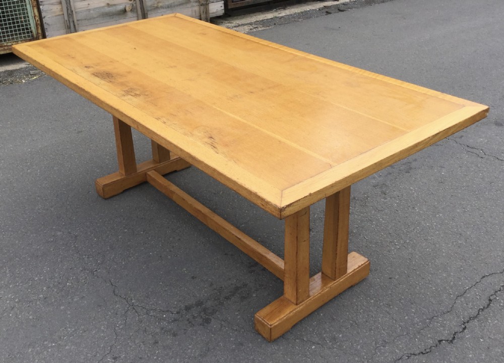 A rectangular golden oak refectory dining table featuring a framed top surface, twin vertical trestle leg supports, and a low central connecting stretcher. View IV