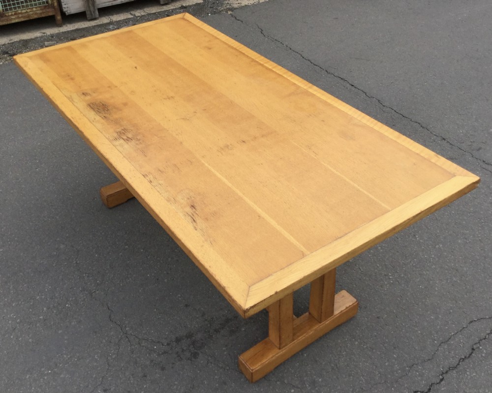 A rectangular golden oak refectory dining table featuring a framed top surface, twin vertical trestle leg supports, and a low central connecting stretcher. View V