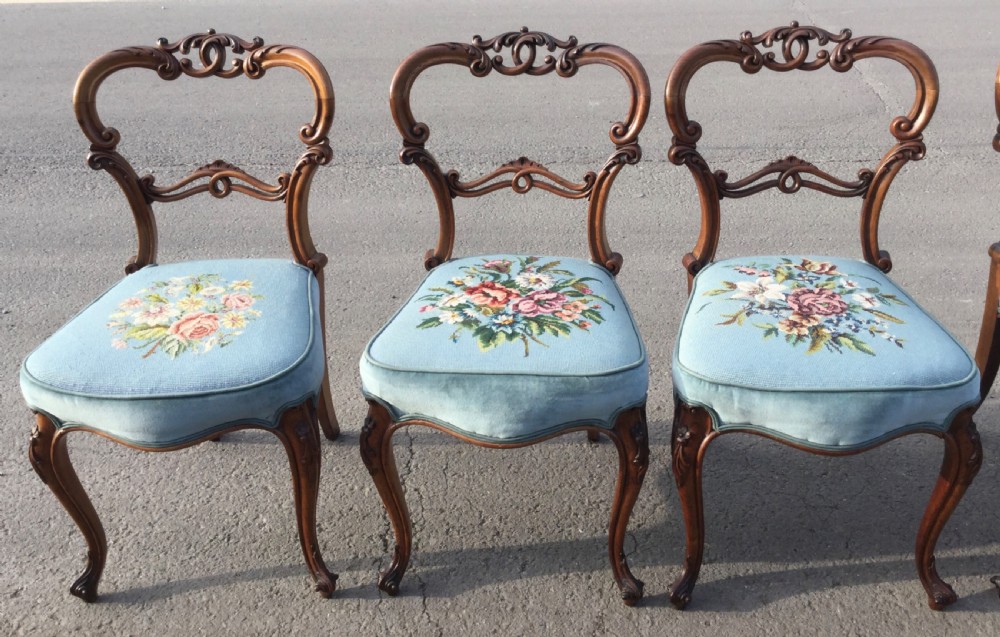 A set of eight Victorian walnut dining chairs featuring carved balloon backs, light blue velvet upholstered seats with central floral needlepoint designs, and cabriole front legs. View IV