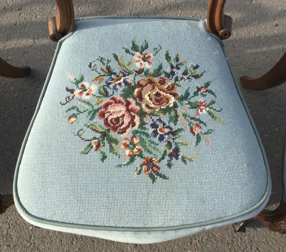 A set of eight Victorian walnut dining chairs featuring carved balloon backs, light blue velvet upholstered seats with central floral needlepoint designs, and cabriole front legs. View VII