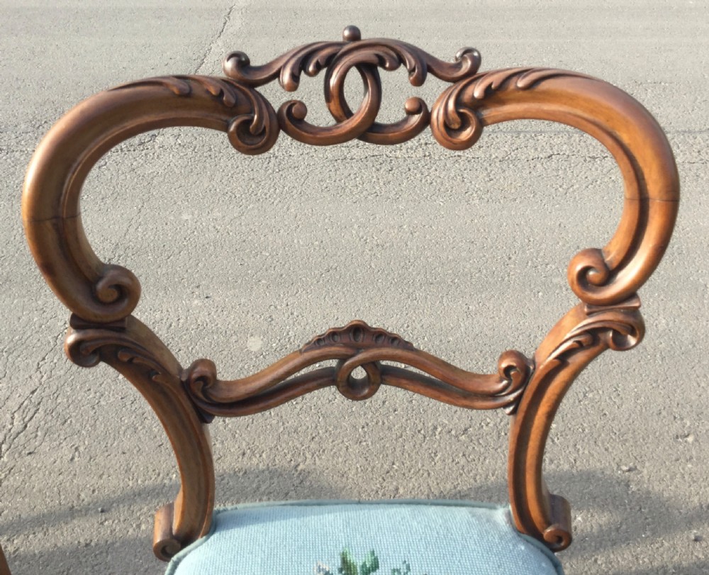 A set of eight Victorian walnut dining chairs featuring carved balloon backs, light blue velvet upholstered seats with central floral needlepoint designs, and cabriole front legs. View VIII