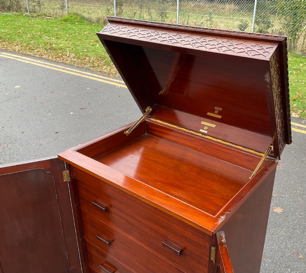 A tall Chippendale style mahogany cabinet featuring carved blind fretwork on the top frieze, arched panel doors, and bracket feet. View VIII