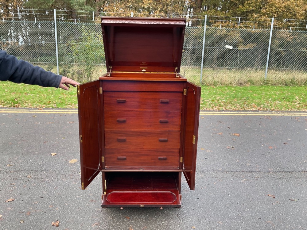 A tall Chippendale style mahogany cabinet featuring carved blind fretwork on the top frieze, arched panel doors, and bracket feet. View IX