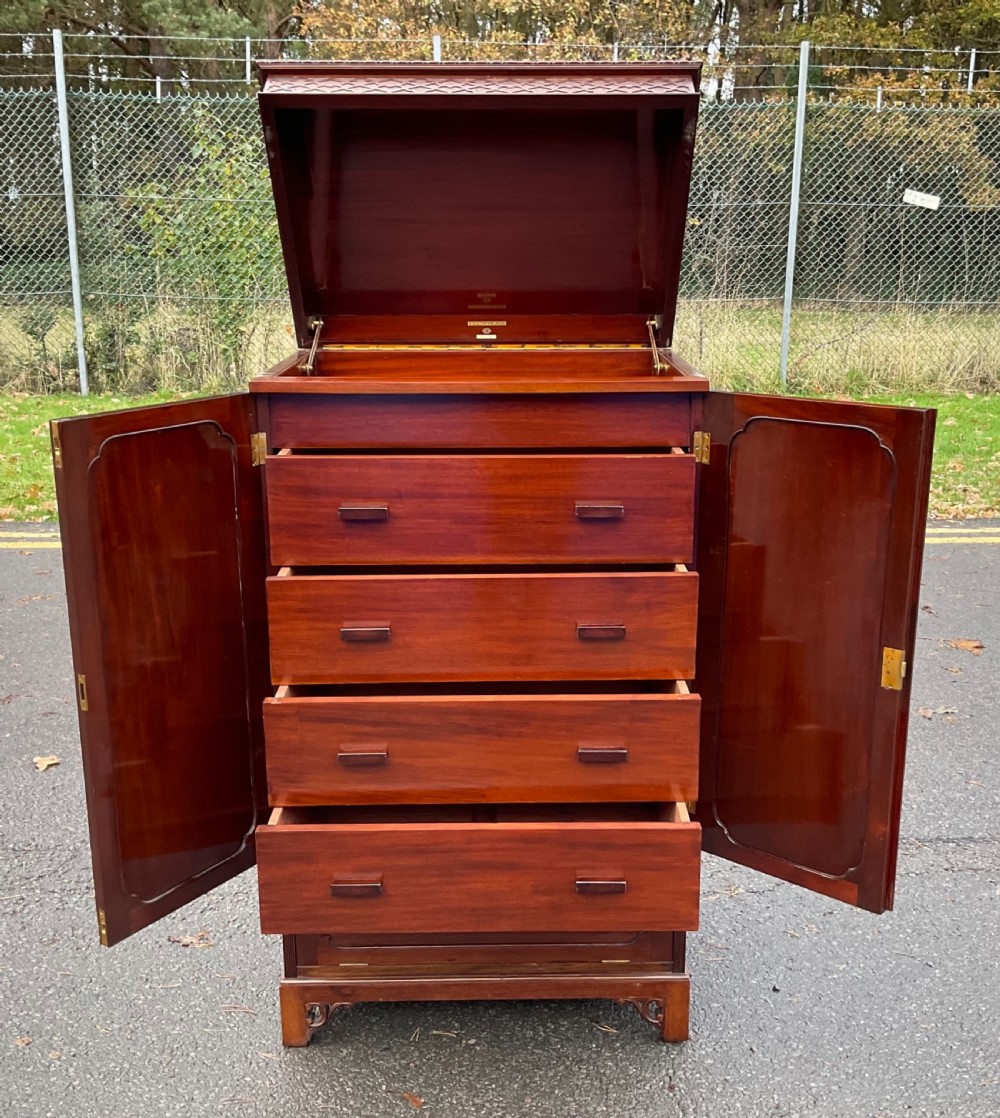 A tall Chippendale style mahogany cabinet featuring carved blind fretwork on the top frieze, arched panel doors, and bracket feet. View X