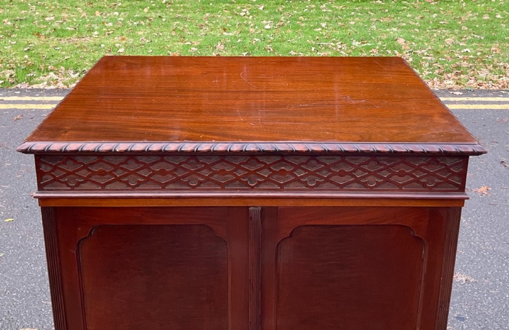 A tall Chippendale style mahogany cabinet featuring carved blind fretwork on the top frieze, arched panel doors, and bracket feet. View XIII