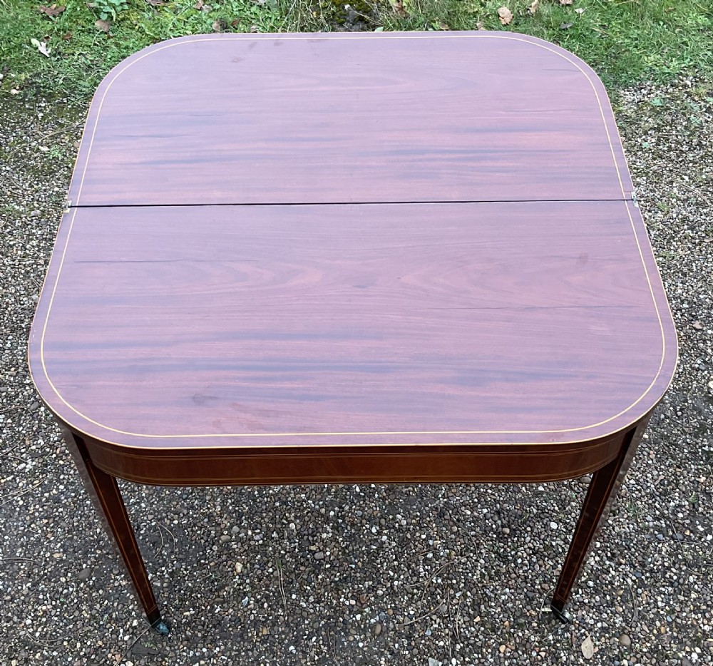 A Georgian inlaid mahogany foldover tea table featuring tapered square legs with brass castors and delicate geometric stringing along the frieze. View VIII