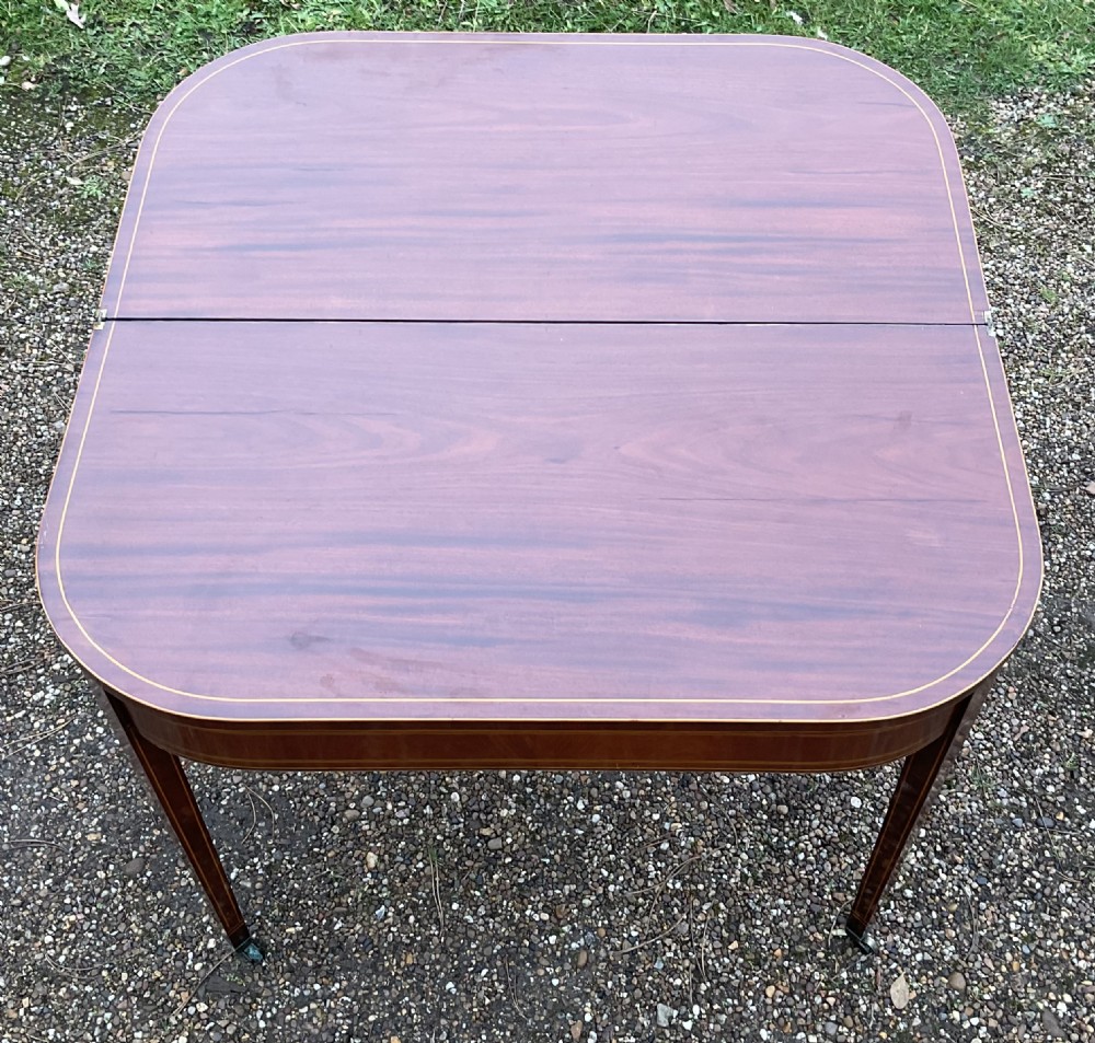 A Georgian inlaid mahogany foldover tea table featuring tapered square legs with brass castors and delicate geometric stringing along the frieze. View IX