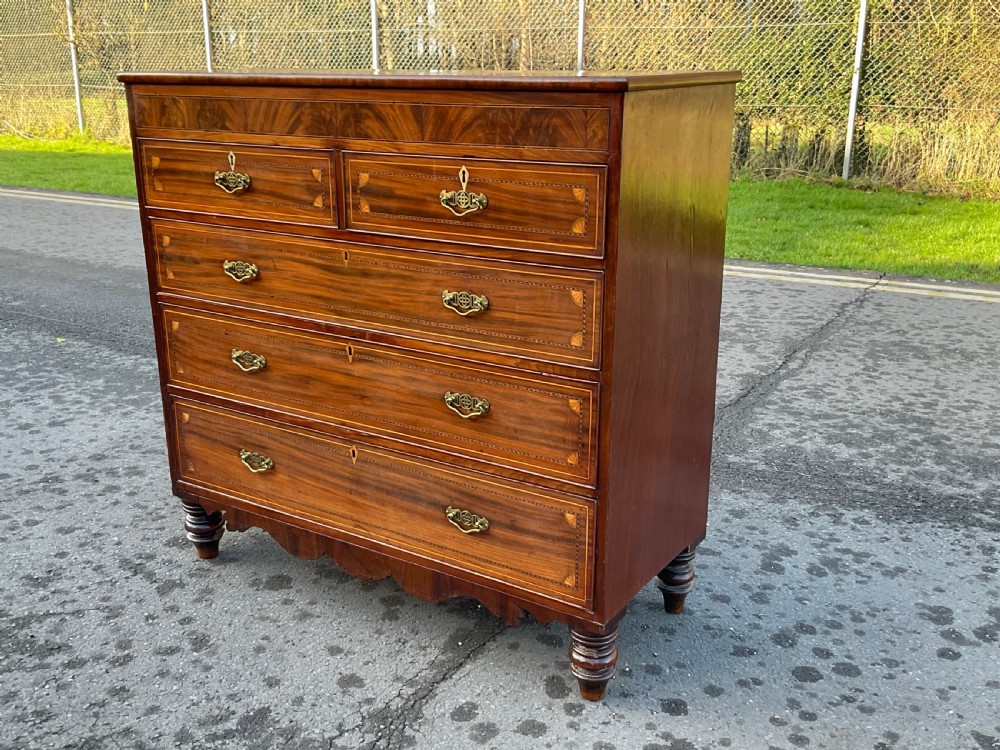 A Georgian mahogany chest of drawers with decorative boxwood inlay, brass handles, and turned foot supports. View II