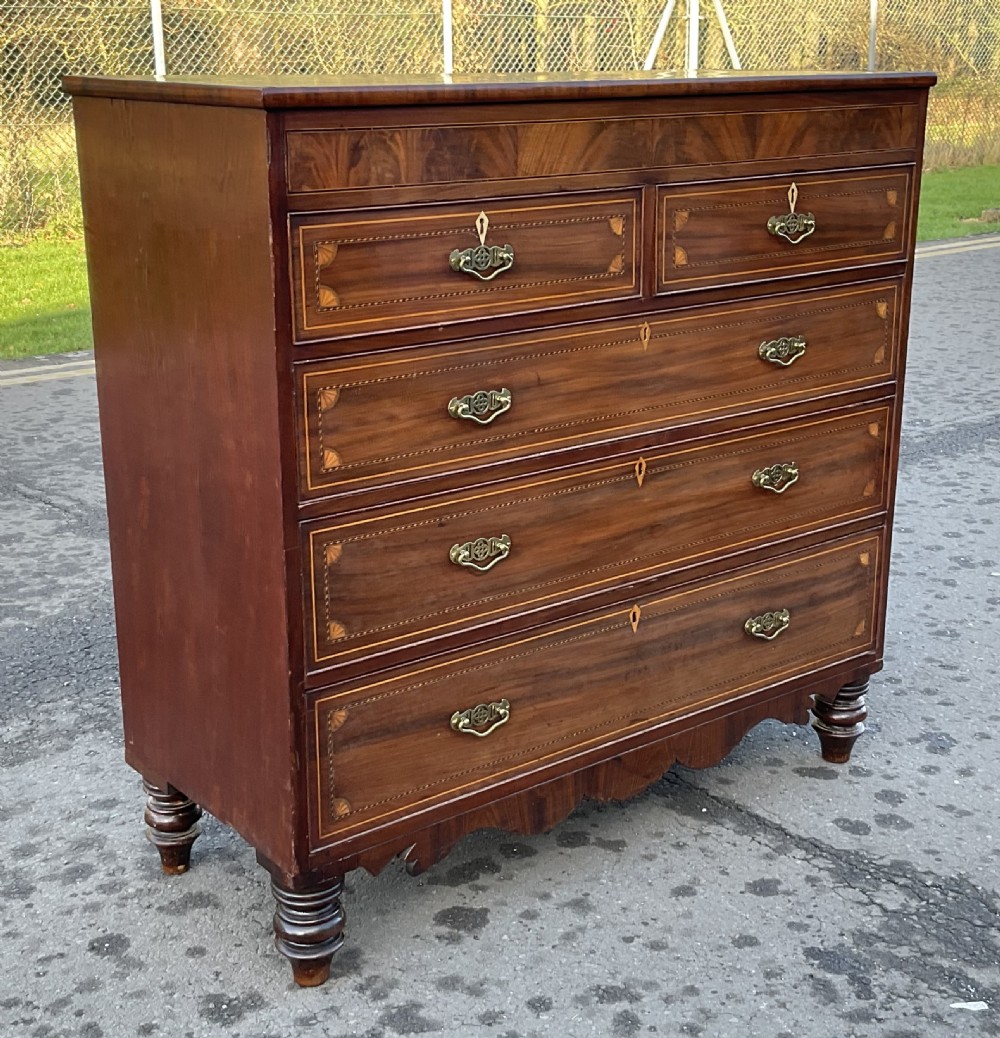 A Georgian mahogany chest of drawers with decorative boxwood inlay, brass handles, and turned foot supports. View IV