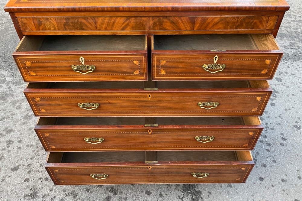 A Georgian mahogany chest of drawers with decorative boxwood inlay, brass handles, and turned foot supports. View IX
