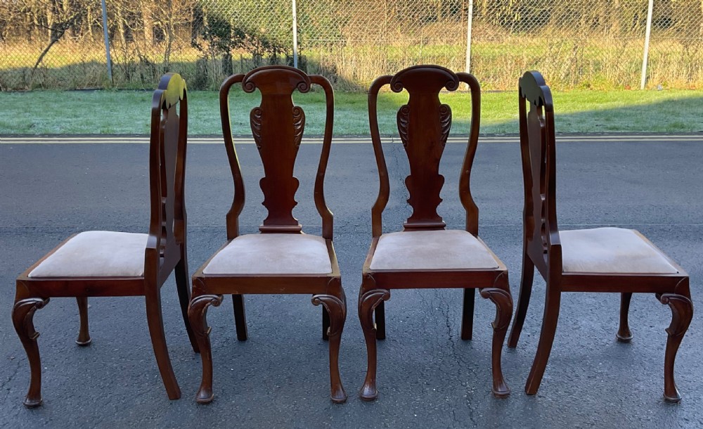 A set of four mahogany highback dining chairs featuring carved vase-shaped back splats, cabriole front legs, and neutral fabric upholstered seats. View V