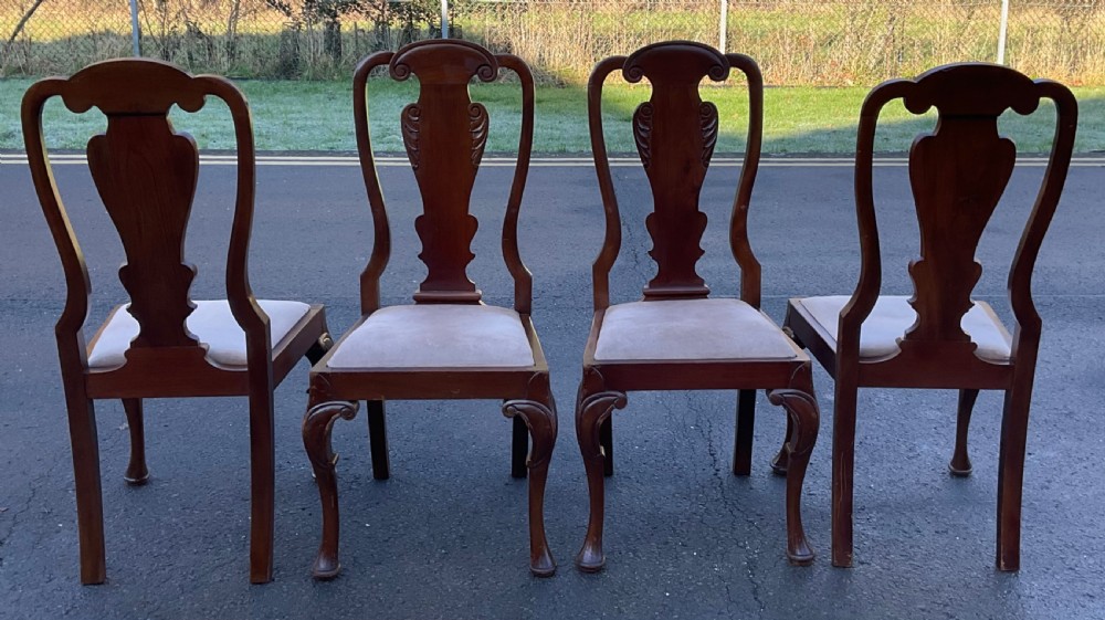 A set of four mahogany highback dining chairs featuring carved vase-shaped back splats, cabriole front legs, and neutral fabric upholstered seats. View VI