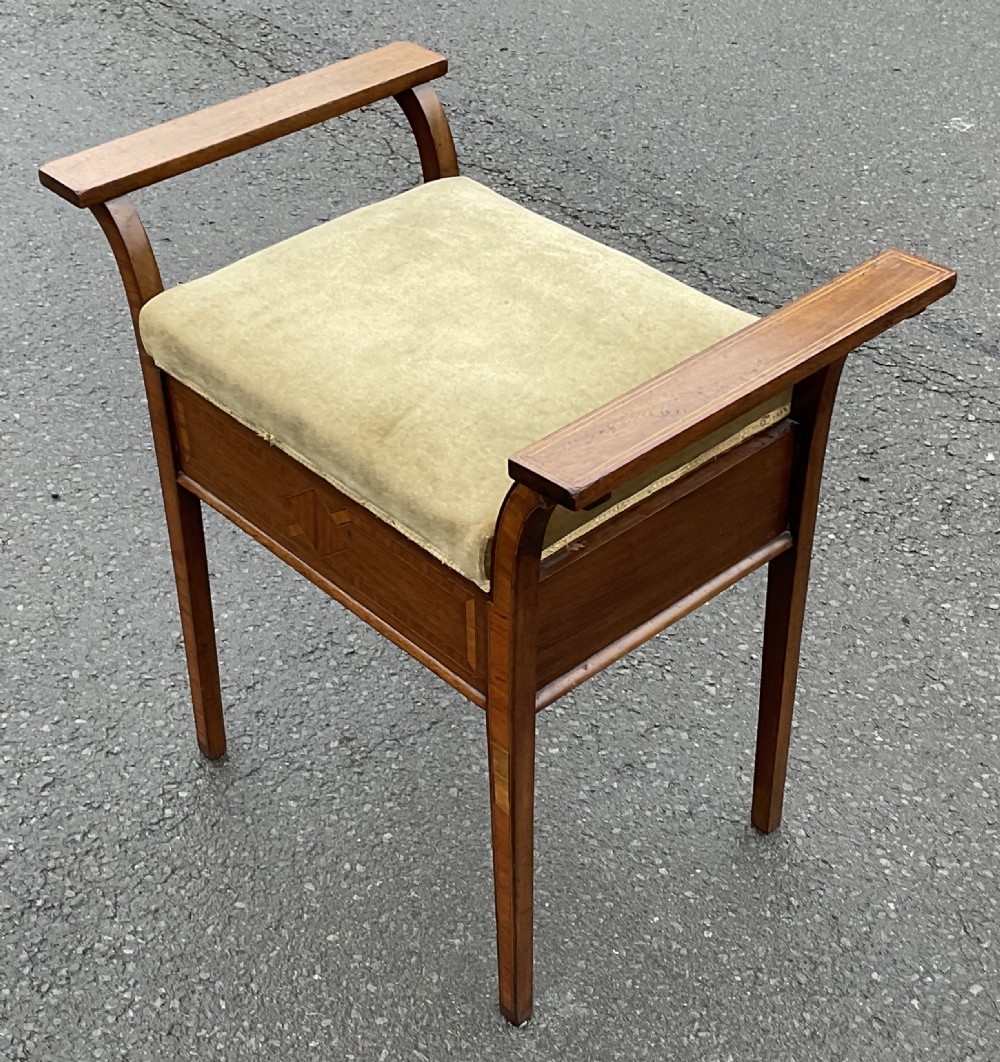 An Edwardian mahogany piano stool with curved side handles, green velvet upholstered seat, and geometric wood inlay on the apron. View V