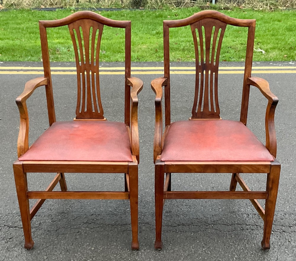 A pair of Georgian style mahogany carver armchairs with pierced splat backs and red leather padded seats.