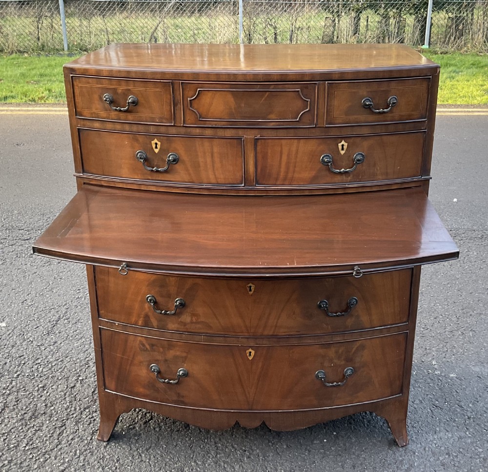 A Georgian style mahogany bowfront chest of drawers featuring brass handles, keyhole escutcheons, subtle string inlay, and splayed bracket feet. View XII