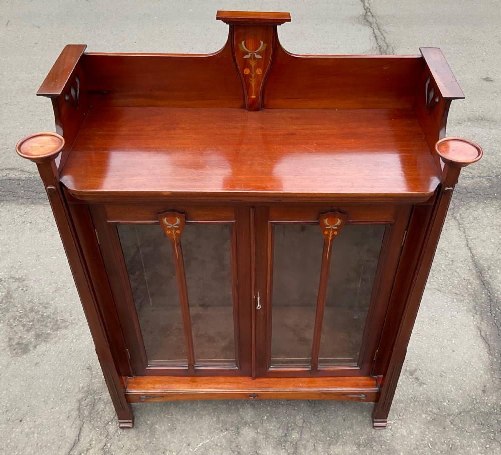 An Art Nouveau mahogany glazed bookcase featuring two glass panel doors with stylised botanical wood inlay and a raised gallery top. View VIII